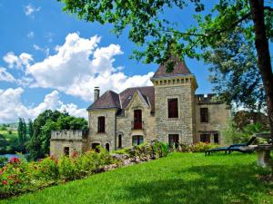 een oud stenen huis met een toren op een groen gazon bij manoir de la malartrie in Vézac