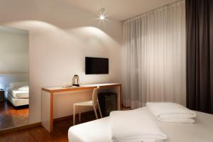 a hotel room with a desk and a bed and a room at Astoria Resort in Riva del Garda