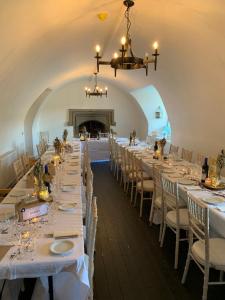 una lunga sala da pranzo con tavoli e sedie bianchi di Branxholme Castle (East Wing Cottage) a Hawick