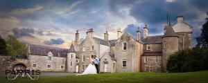 
a bride and groom standing in front of a castle at Branxholme Castle (Bed & Breakfast) in Hawick
