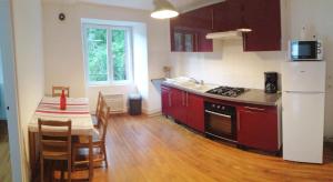 a kitchen with red cabinets and a table and a kitchen with a refrigerator at la violette in Ferrières-Saint-Mary
