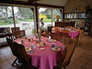 une salle à manger avec des tables, des chaises et un tissu de table rose dans l'établissement les marronniers, à Cambremer