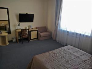 a hotel room with a bed and a chair and a television at Baza Otdykha Kazaki in Aleksandrovka