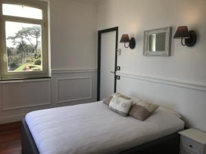 een slaapkamer met een bed met witte lakens en een raam bij Villa Ker Eole Vue Mer in Dinard