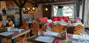 um restaurante com mesas de madeira e cadeiras com copos de vinho em Le Taconet em Le Praz de Lys