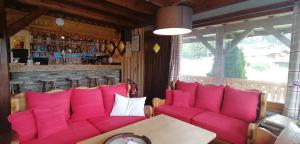 une chambre avec des canapés roses, une table et un bar dans l'établissement Le Taconet, à Praz de Lys - Sommand