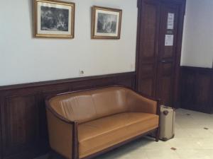 a leather bench in a room with two pictures on the wall at Le Jardin d'Homps in Homps