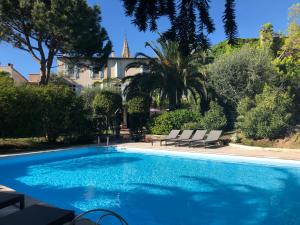 a swimming pool with two chairs and a house at Le Jardin d'Homps in Homps