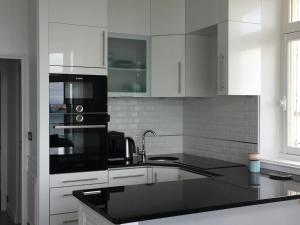 una cocina con armarios blancos y electrodomésticos negros en Villa XIXe Vue mer en Dinard