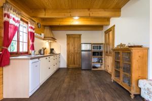 a kitchen with white cabinets and wooden ceilings at Roubenka Háj in Jindřichovice