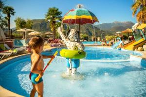 a young child playing in a swimming pool with an umbrella at Weekend Glamping Resort in San Felice del Benaco
