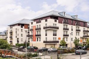 un gran edificio blanco con coches estacionados frente a él en Aparthotel Adagio Access Carrières Sous Poissy, en Carrières-sous-Poissy