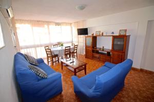 sala de estar con sofá azul y mesa en Apartamento Benidorm 3, en Benidorm