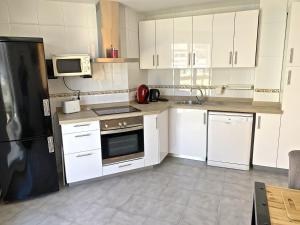 a kitchen with white cabinets and a black refrigerator at Apartamento Benidorm II in Benidorm