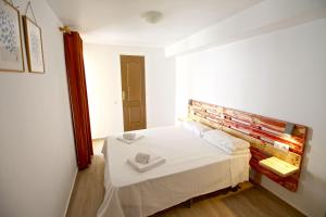 een slaapkamer met een wit bed en een houten hoofdeinde bij Apartamento Benidorm II in Benidorm