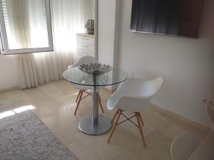uma mesa de vidro e duas cadeiras brancas num quarto em Estudio Playa del Postiguet em Alicante