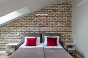 una camera da letto con un muro di mattoni e un letto con cuscini rossi di Somnia Apartments a Vilnius