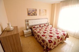 Un dormitorio con una cama con colcha floral y una ventana. en Apartamento Las Torres, en El Campello 17 fotos más