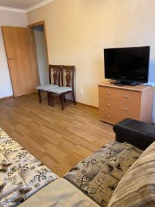 uma sala de estar com uma cama e uma televisão de ecrã plano em Домашний уют em Karaganda