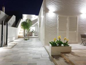 un couloir d'une maison aux murs blancs et aux fleurs dans l'établissement La Baia Apartments, à Torre Lapillo
