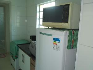 um micro-ondas em cima de um frigorífico numa cozinha em Apartamento à 50 metros da praia - Itanhaém em Itanhaém