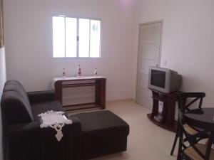 a living room with a couch and a tv at Apartamento à 50 metros da praia - Itanhaém in Itanhaém
