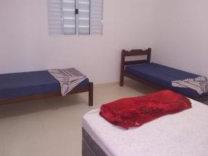 a room with two beds and a chair in it at Apartamento à 50 metros da praia - Itanhaém in Itanhaém