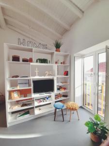 a white living room with a tv and a stool at Casa Vinte & Cinco Alojamento Local in Penha Garcia