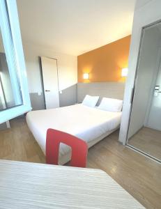 a hotel room with two beds and a red chair at Première Classe Martigues in Martigues