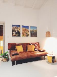 a brown leather couch in a room with pictures on the wall at Casa Vinte & Cinco Alojamento Local in Penha Garcia