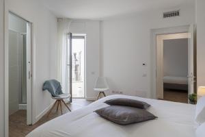 een witte slaapkamer met een bed en een stoel bij Deluxe Apartments by Wonderful Italy in Genua