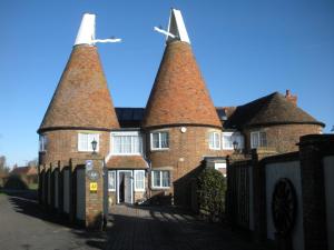 an old brick house with two towers on a street at Manor Farm Oast in Winchelsea
