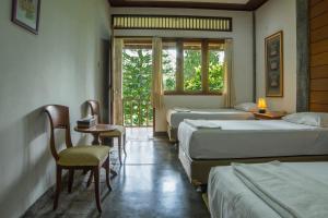a hotel room with three beds and a window at Griya Dunamis by SABDA in Puncak