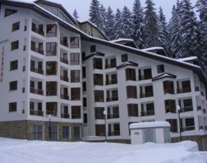 un grand immeuble d'appartements sous la neige avec des arbres dans l'établissement Golden Box Pamporovo, à Pamporovo