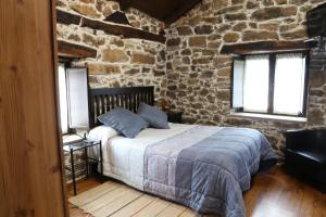 Un dormitorio con una cama en una pared de piedra. en Casa Rural Madreselva, en Navelgas 47 fotos más