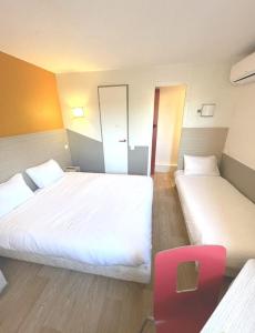 una habitación de hotel con 2 camas y una silla roja en Première Classe Martigues, en Martigues