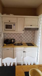 eine Küche mit weißen Schränken und einem Waschbecken in der Unterkunft Karl Theo Am Wald in Westerland