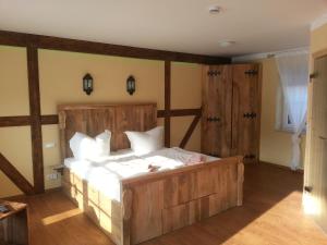 a bedroom with a large wooden bed with white sheets at Pension zum Holzpantoffelmacher in Burg