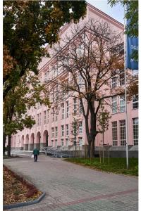 a person walking in front of a pink building at Kwiatowa Warsaw Apartment in Warsaw