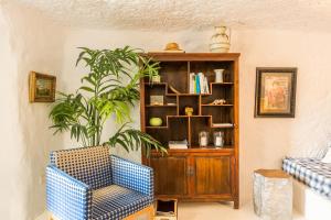 a living room with a chair and a book shelf at Cueva de Sacromonte in Teror