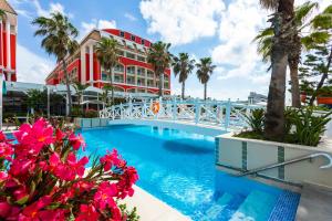 a swimming pool with a bridge and palm trees and a building at Orange County Belek in Belek