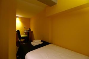 a yellow room with a bed and a chair at City Hotel Amsterdam in Amsterdam