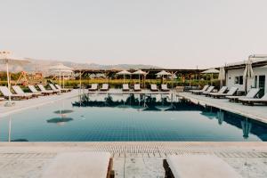 uma piscina num resort com cadeiras e guarda-sóis em Sails on Kos Ecolux Tented Village em Marmari