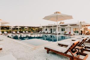 a swimming pool with lounge chairs and an umbrella at Sails on Kos Ecolux Tented Village in Marmari