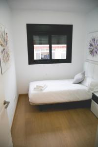 a bedroom with a white bed and white walls at Be Free Granada in Granada