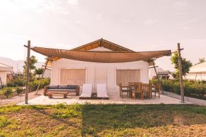 a pavilion with a couch and a table and chairs at Sails on Kos Ecolux Tented Village in Marmari