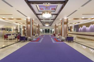 a hotel lobby with a purple carpet and chairs and tables at Orange County Belek in Belek