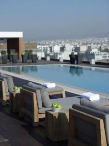 a swimming pool with chairs and a table on a building at The Met Hotel Thessaloniki, a Member of Design Hotels in Thessaloniki