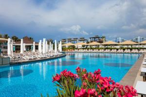 a large swimming pool with chairs and flowers at Orange County Belek in Belek