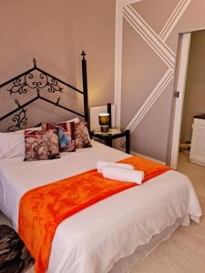 1 dormitorio con 1 cama grande con manta naranja en Angel's Corner en Ciudad del Cabo